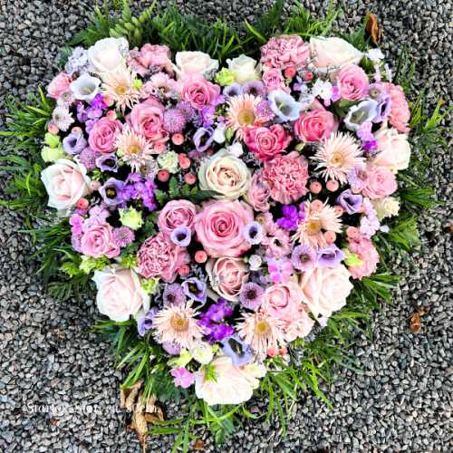 Begravningshjärta i mixade blommor i storleken stor. Hjärtat går i rosa och lila toner.